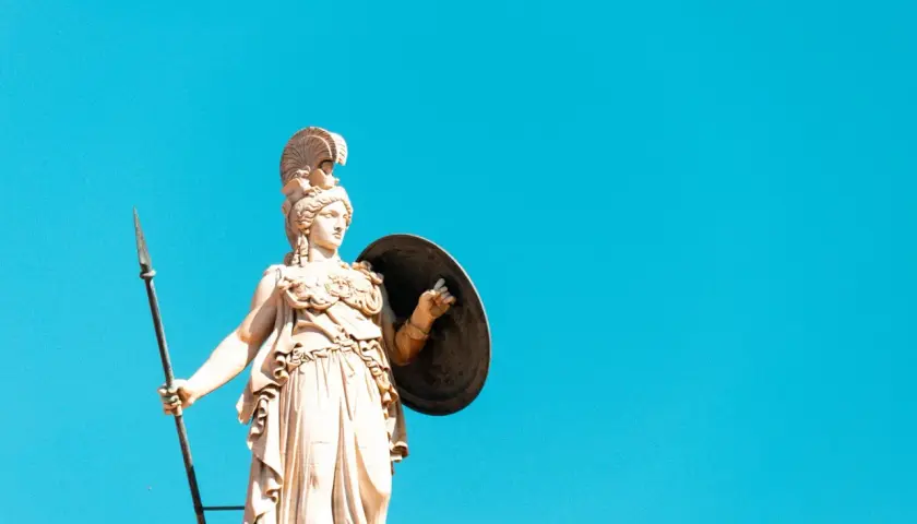 Statua di Atena, dea greca della giovinezza e della saggezza, con lancia e scudo contro un cielo azzurro.