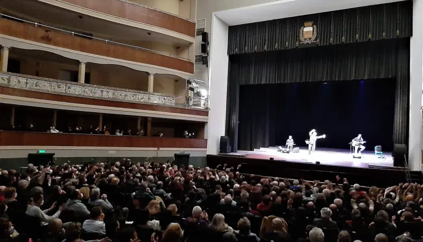 Un pubblico numeroso applaude sul palco, dove tre artisti si esibiscono in quello che potrebbe essere il primo teatro in Italia.
