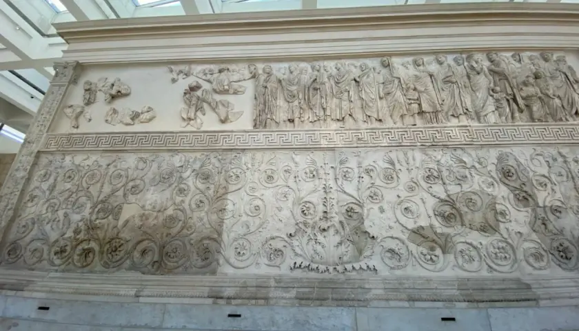 Rilievi dell'Ara Pacis: una processione di figure e decorazioni floreali intricate, testimonianza dell'arte romana.