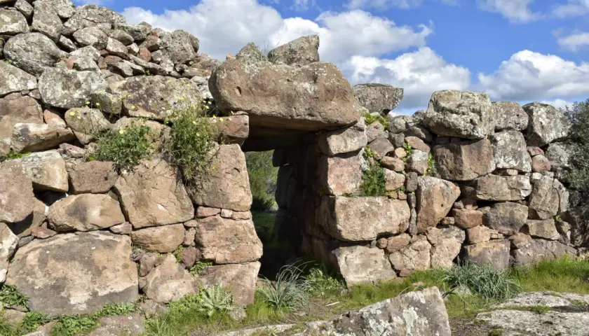 Antica porta in pietra del complesso megalitico di Monte Baranta, con vegetazione che cresce tra le rocce.