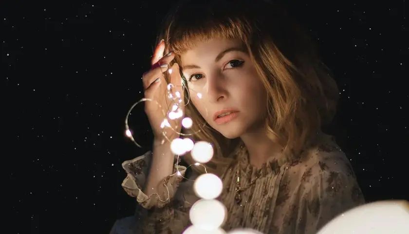 Una ragazza con luci scintillanti tra le dita, come un filo di Arianna che illumina il buio.
