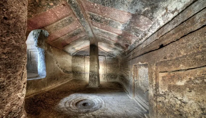 Interno di domus de janas dipinte, con pilastro centrale e decorazioni circolari sul pavimento.
