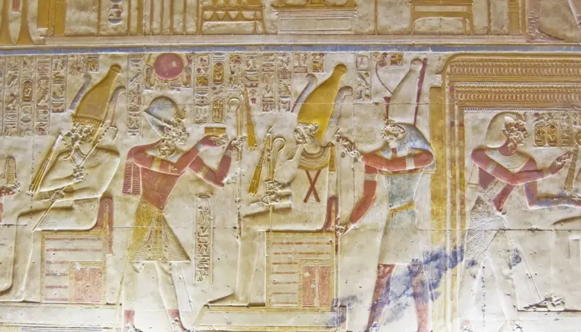 Antico rilievo egizio con figure che adorano un dio min. Geroglifici e colori vivaci.