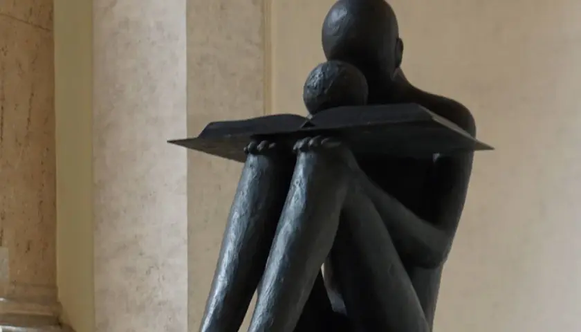 Statua di una figura che legge, immersa in un momento di riflessione, quasi un sinonimo di accidia intellettuale.