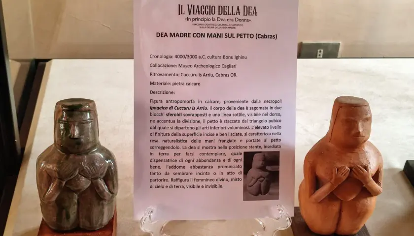 Due statue neolitiche di dea madre con le mani sul petto, una in pietra calcarea verde scuro, l'altra in terracotta.