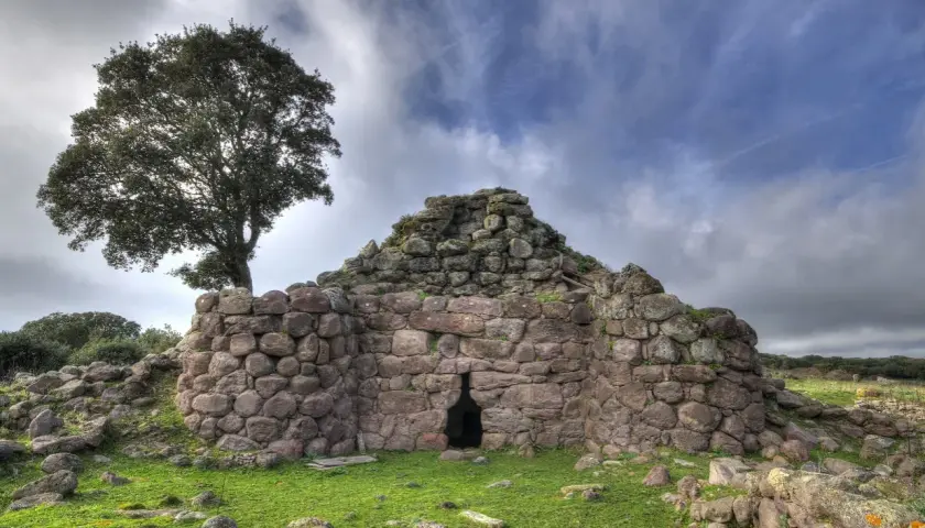 Il nuraghe Appiu, con la sua imponente struttura in pietra, si erge solitario sotto un cielo nuvoloso, testimone di antiche storie.
