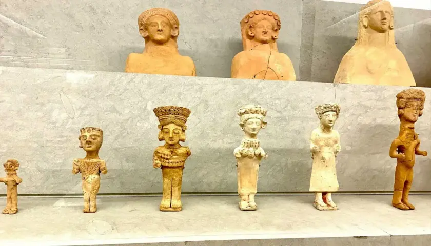 Antiche statuette in terracotta, tra cui una dea punica della fertilità, esposte su una mensola.