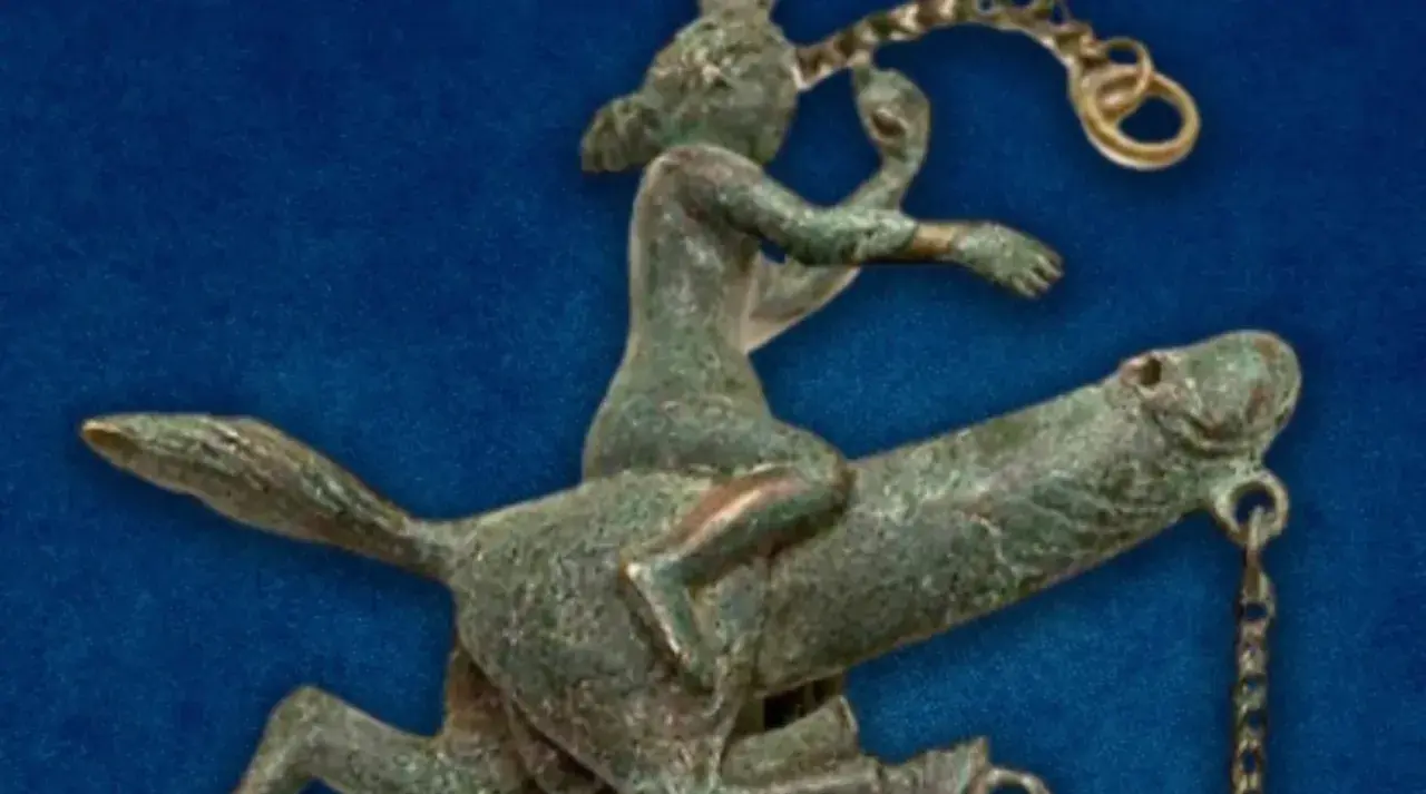 Antica statuetta in bronzo di un cavaliere che cavalca un cavallo, forse un **fallo dio pan** in movimento.