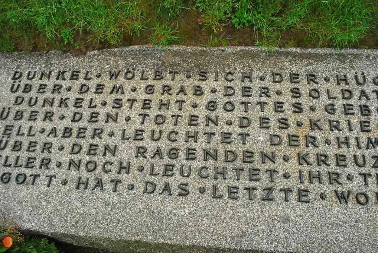 Dettaglio di un'iscrizione in tedesco su una lapide in un cimitero tedesco in Normandia. Le parole evocano oscurità e speranza.