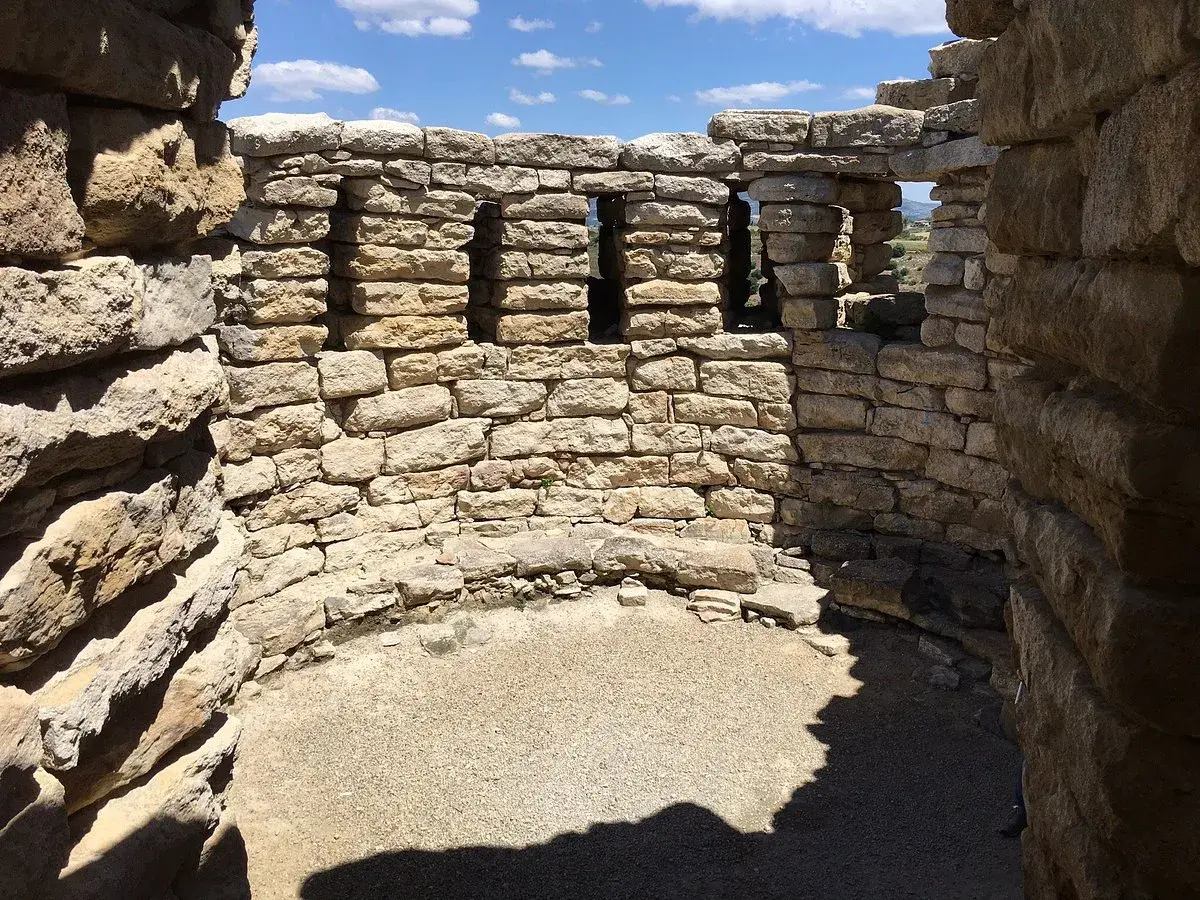Interno del nuraghe Su Mulinu, con mura in pietra grezza e finestre quadrate che si affacciano sul paesaggio.