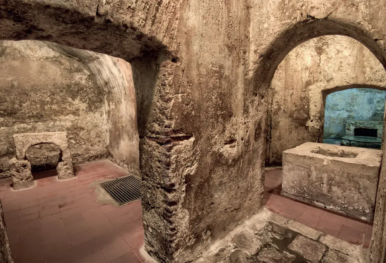Interno dell'ipogeo San Salvatore: archi in pietra grezza, vasca in cemento, pavimenti in cotto e un antico altare.