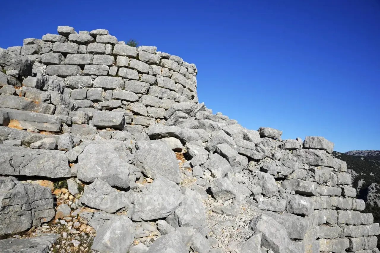 Rovine del nuraghe Barru, con pietre grigie e un cielo blu intenso.