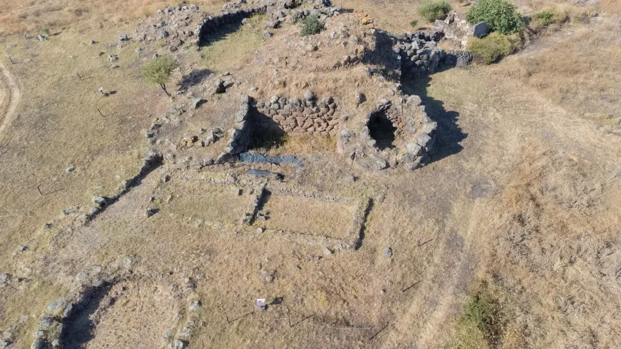 Resti di un antico villaggio nuragico, con pietre che delineano le fondamenta di antiche abitazioni e mura.