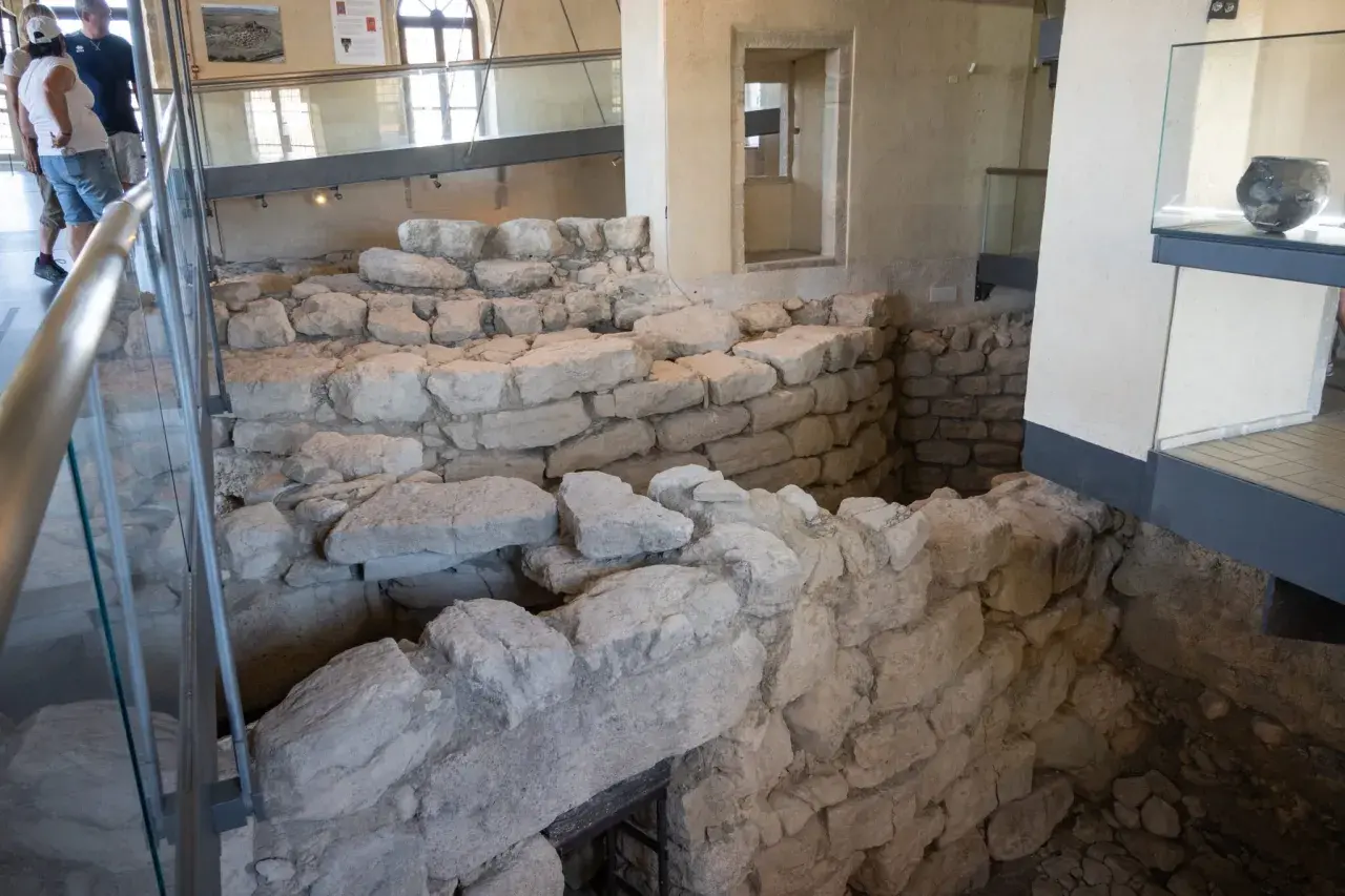 Interno del nuraghe di Barumini, con antiche mura in pietra e reperti archeologici esposti.