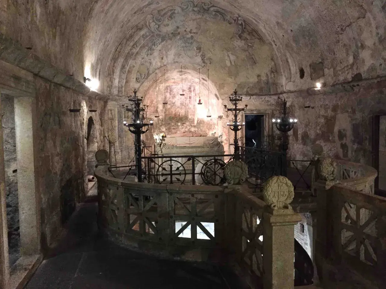 Interno della cripta di Santa Cristina, con affreschi antichi, candelabri e un sarcofago.
