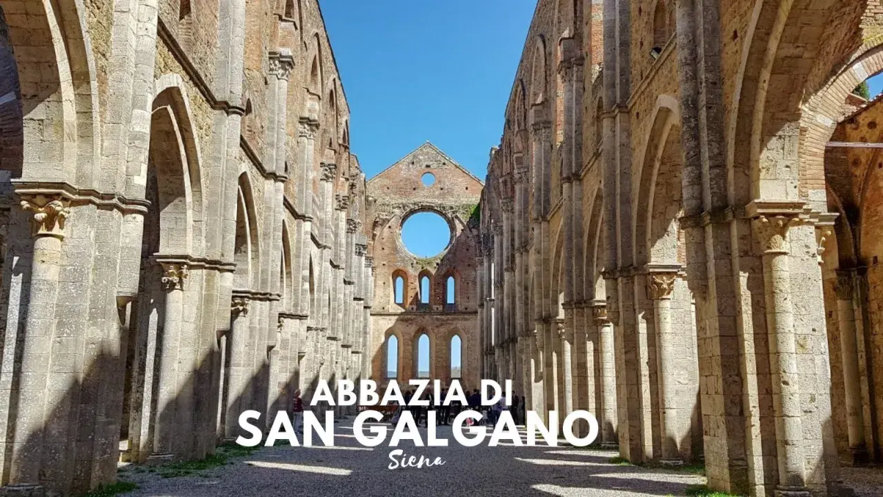L'abbazia di San Galgano, un'imponente rovina nel cuore di un querceto, si erge maestosa sotto un cielo azzurro.