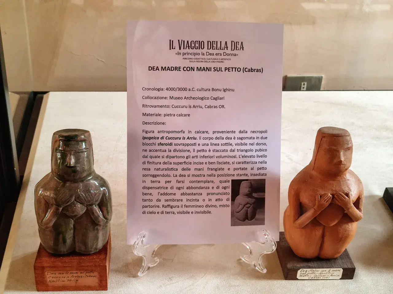 Due statue neolitiche di dea madre con le mani sul petto, una in pietra calcarea verde scuro, l'altra in terracotta.