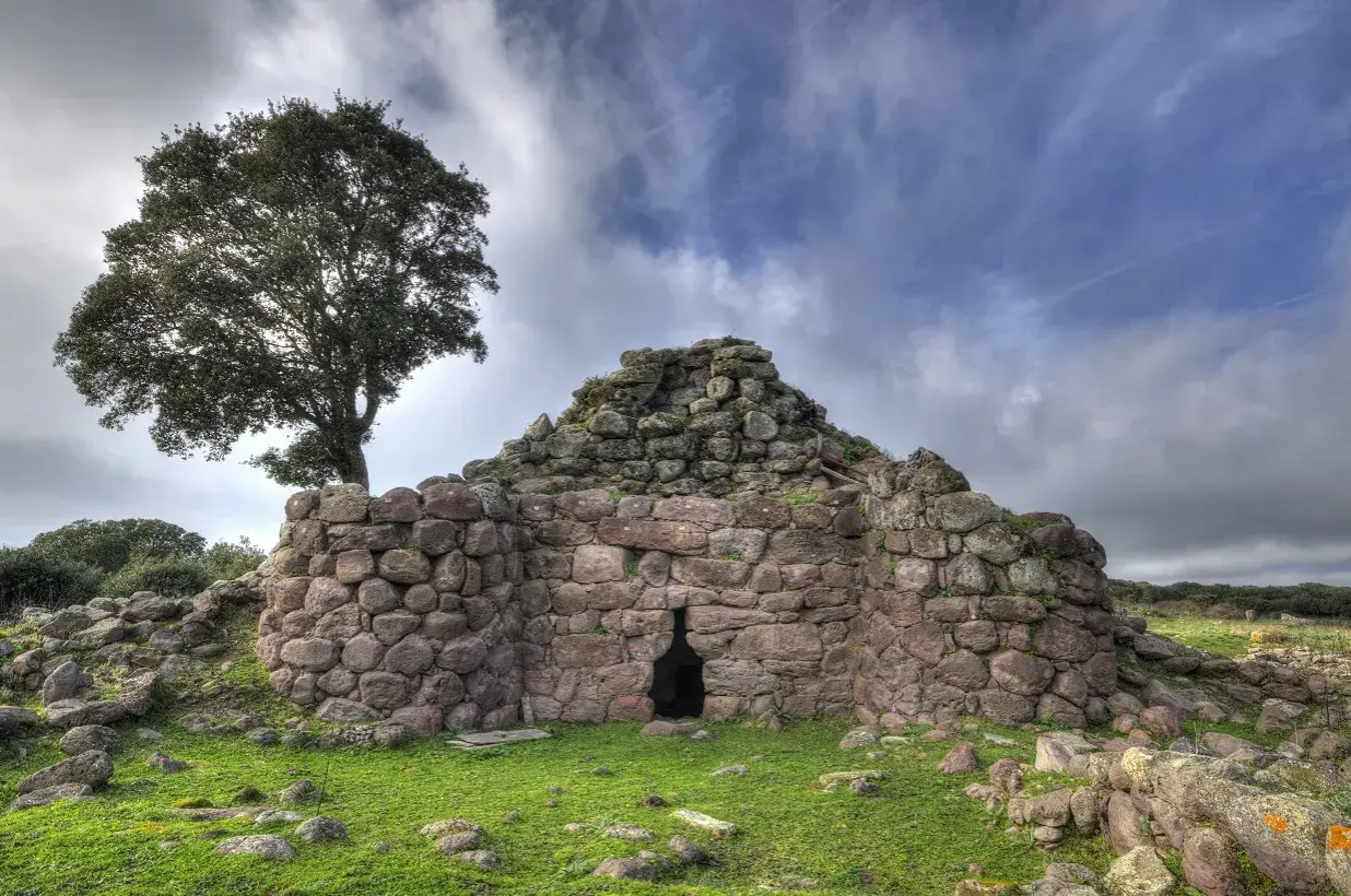 Il nuraghe Appiu, con la sua imponente struttura in pietra, si erge solitario sotto un cielo nuvoloso, testimone di antiche storie.