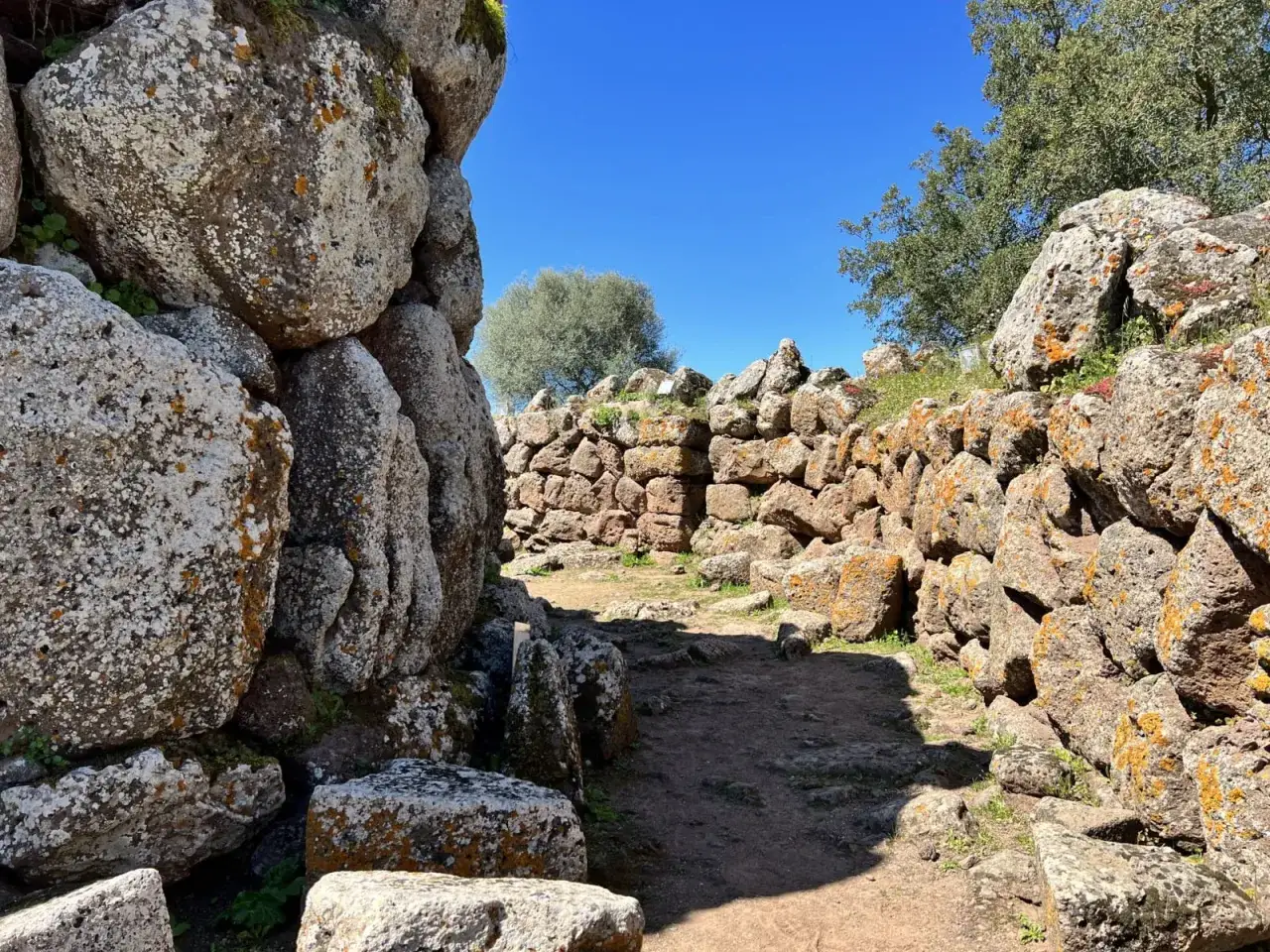 Antiche mura di pietra del nuraghe Arrubiu sotto un cielo azzurro.