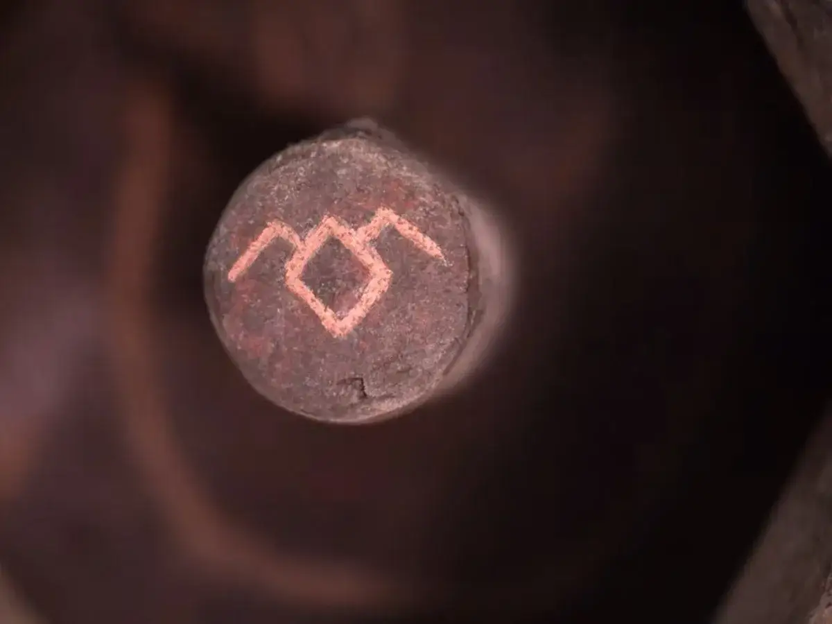 Un simbolo iconico di Twin Peaks, un rombo con due linee a zig-zag sopra, inciso su un oggetto rotondo e scuro.