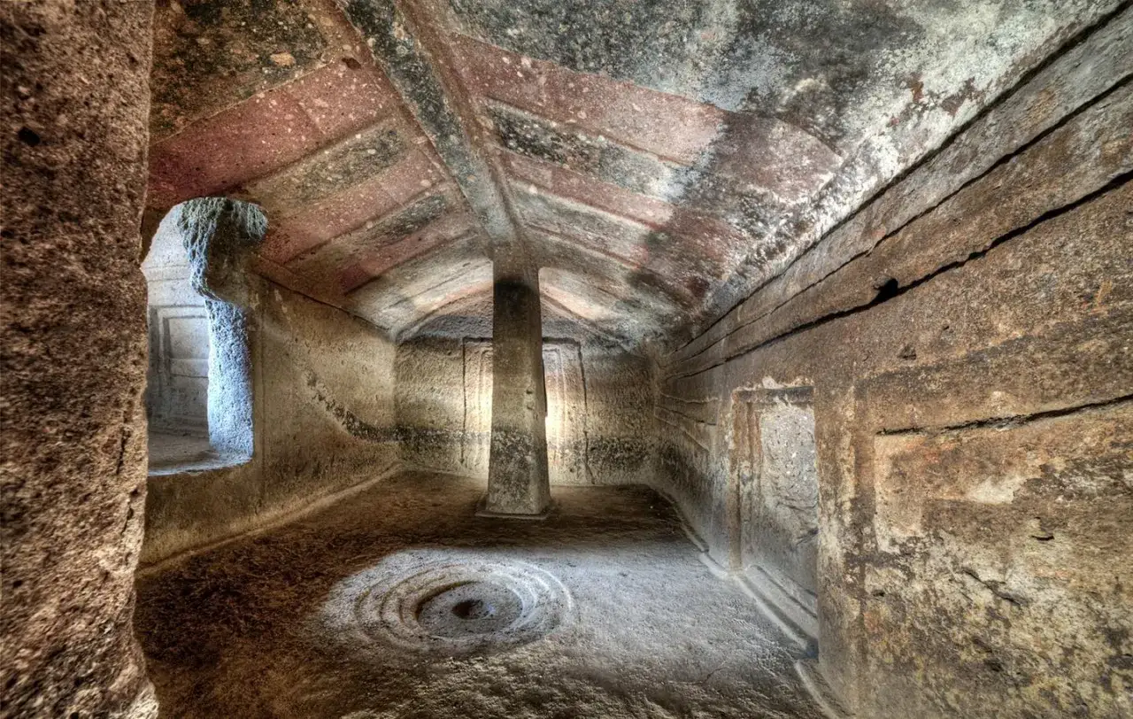 Interno di domus de janas dipinte, con soffitto a volta e pilastro centrale. Sul pavimento, un cerchio concentrico inciso.