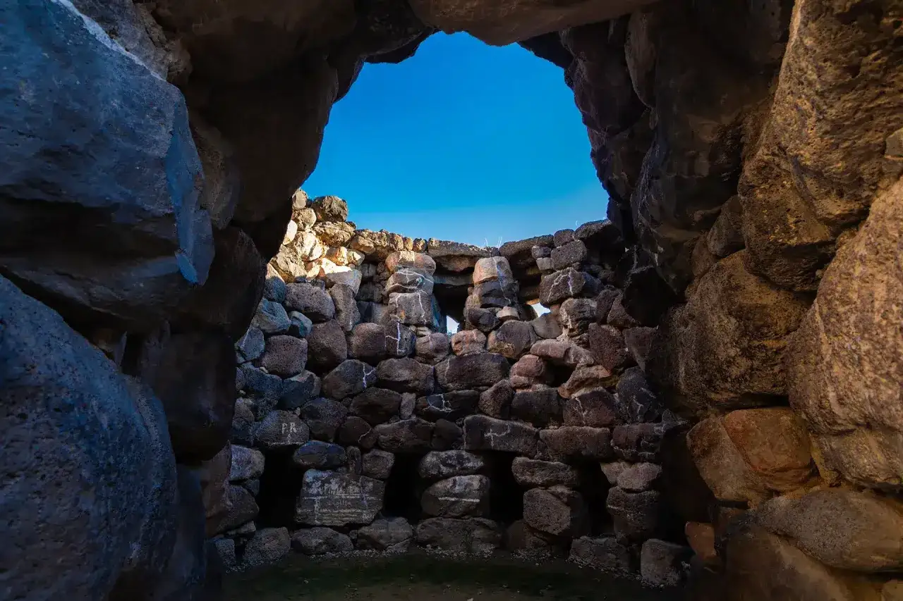 Interno del nuraghe di Barumini, con le sue antiche pietre che si stagliano contro un cielo azzurro intenso.