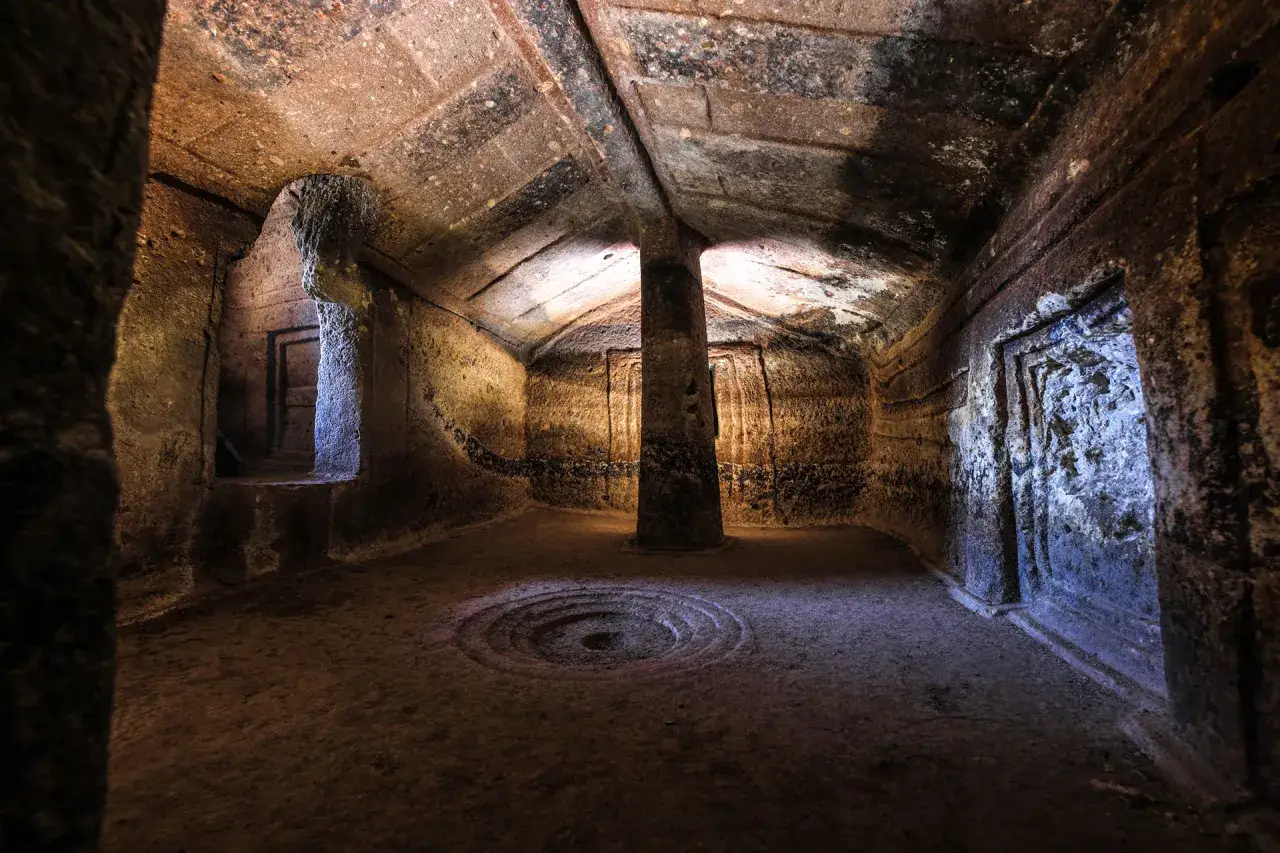 Interno di una domus de janas a Putifigari, con pilastro centrale e decorazioni circolari sul pavimento.
