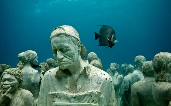 Un gruppo di statue giganti mare, con un pesce che nuota tra loro, crea un'atmosfera surreale.
